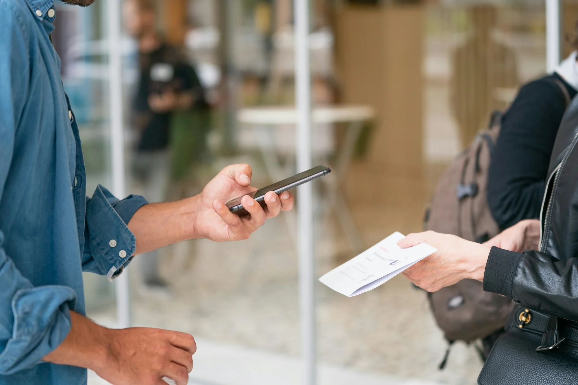 Zwei Personen tauschen Kontaktdaten per QR-Code-Scan auf einer Messe – digitale Visitenkarte in Aktion
